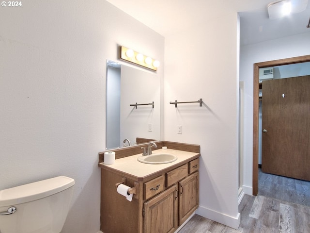 bathroom featuring wood-type flooring, vanity, and toilet