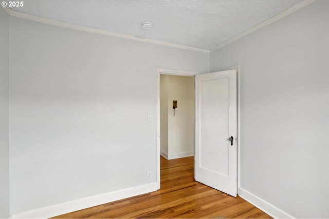 unfurnished room featuring hardwood / wood-style floors, crown molding, and a textured ceiling