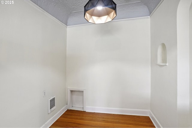 unfurnished room with wood-type flooring, a textured ceiling, and ornamental molding