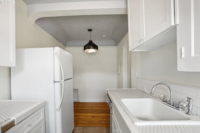 kitchen featuring sink, pendant lighting, white refrigerator, hardwood / wood-style flooring, and white cabinets