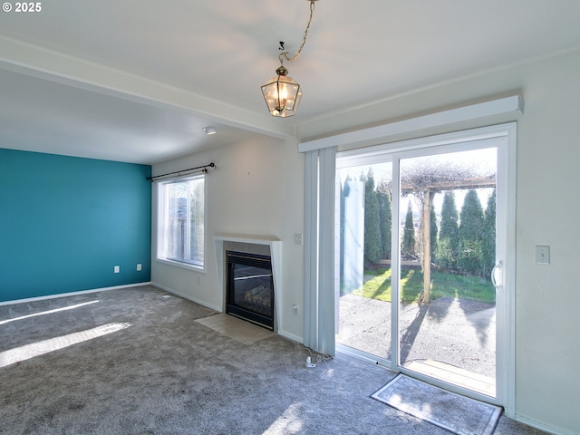 unfurnished living room with beamed ceiling, plenty of natural light, and carpet flooring