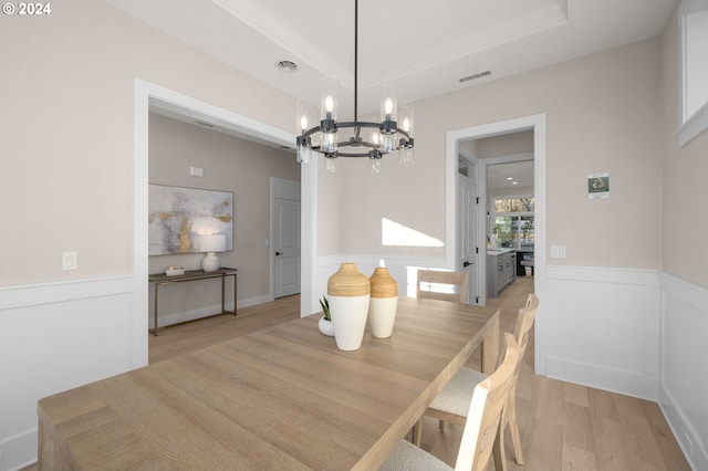 dining room featuring a raised ceiling, light hardwood / wood-style flooring, and a notable chandelier