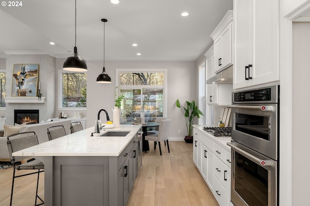 kitchen featuring white cabinets, a kitchen bar, light stone counters, and sink