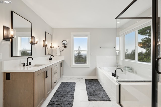 bathroom with a wealth of natural light, vanity, and tiled tub