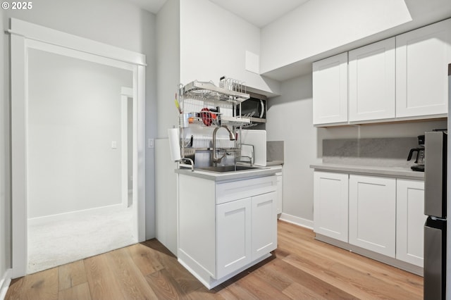 kitchen featuring white cabinets, light wood-type flooring, and sink