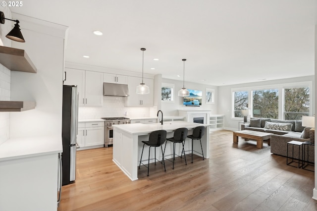 kitchen with white cabinetry, a kitchen breakfast bar, backsplash, pendant lighting, and appliances with stainless steel finishes