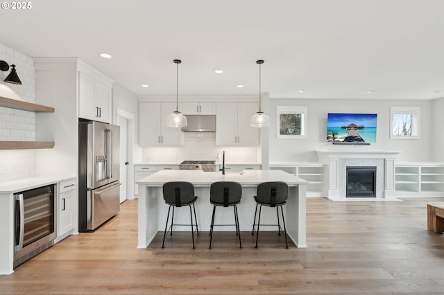 kitchen with stainless steel refrigerator with ice dispenser, wine cooler, decorative backsplash, decorative light fixtures, and white cabinetry