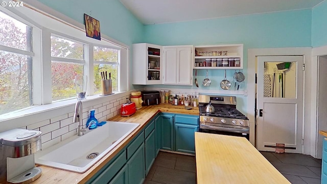 kitchen with gas range, sink, wood counters, tasteful backsplash, and dark tile patterned floors