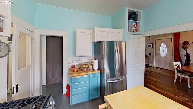 kitchen featuring dark wood-type flooring, butcher block countertops, backsplash, white cabinets, and appliances with stainless steel finishes