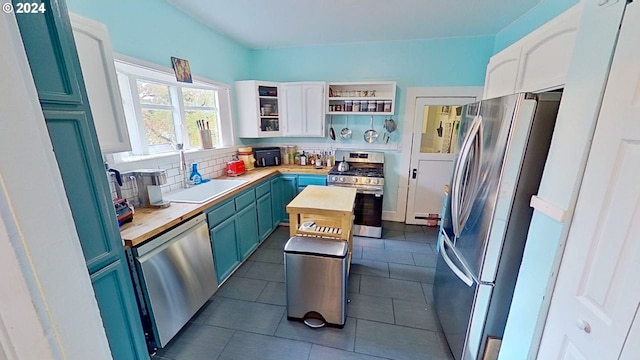 kitchen with butcher block countertops, white cabinets, blue cabinetry, and stainless steel appliances