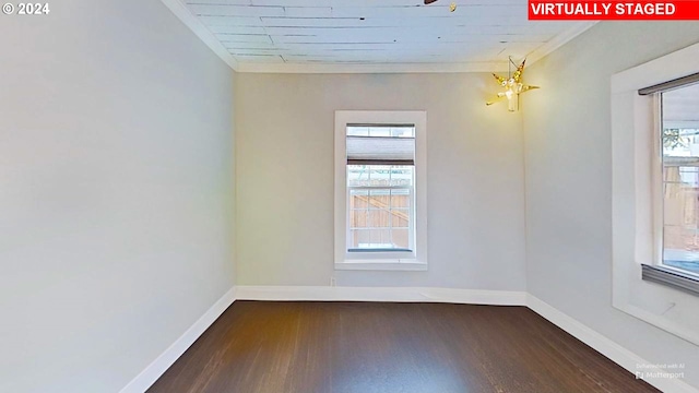 empty room featuring dark hardwood / wood-style flooring, an inviting chandelier, and crown molding