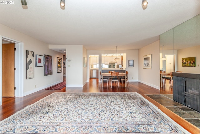 dining space featuring a textured ceiling, wood finished floors, and baseboards