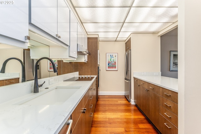 kitchen featuring brown cabinetry, a sink, and freestanding refrigerator