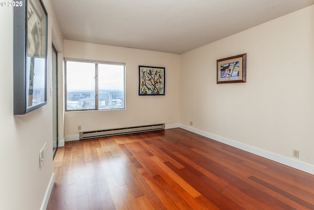 unfurnished room featuring wood-type flooring, baseboards, baseboard heating, and a textured ceiling