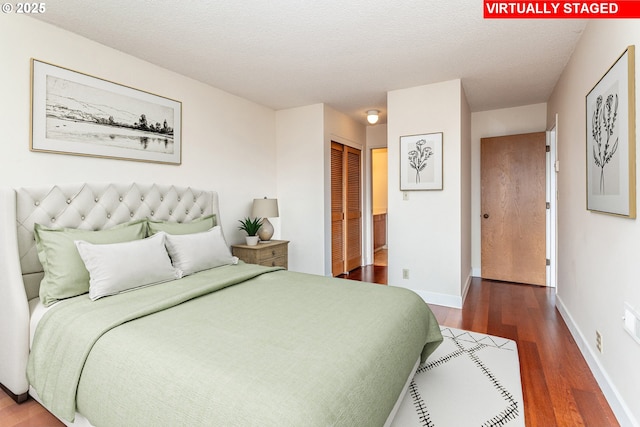 bedroom with a closet, a textured ceiling, baseboards, and wood finished floors