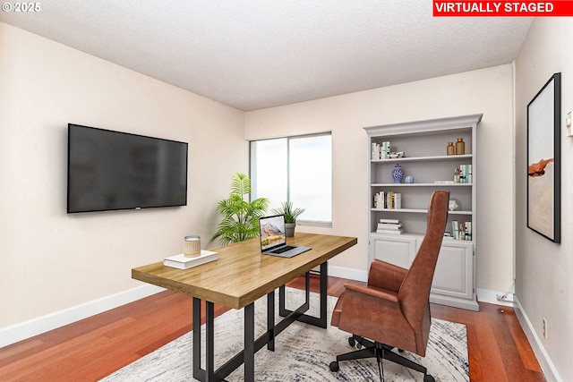 office area with a textured ceiling, baseboards, and wood finished floors