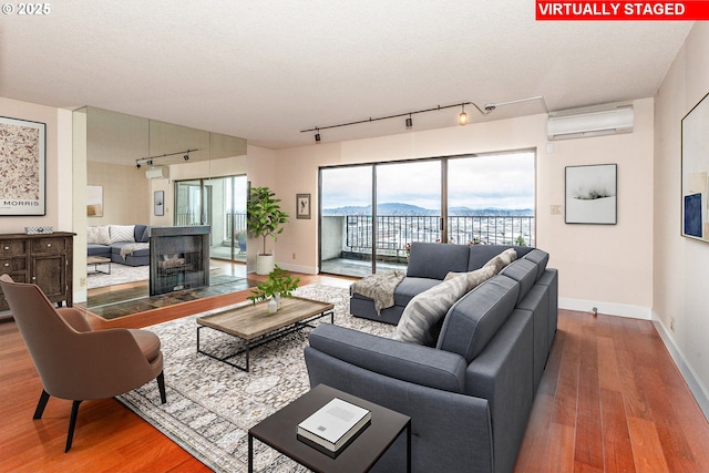 living room featuring baseboards, a mountain view, wood finished floors, and a wall mounted AC