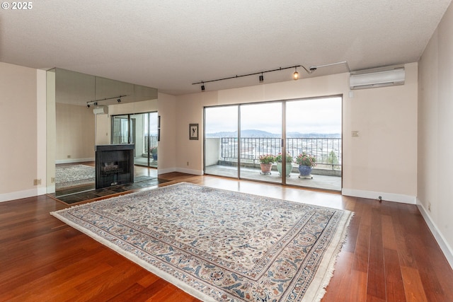 unfurnished living room featuring a textured ceiling, a wall mounted air conditioner, wood finished floors, and a mountain view