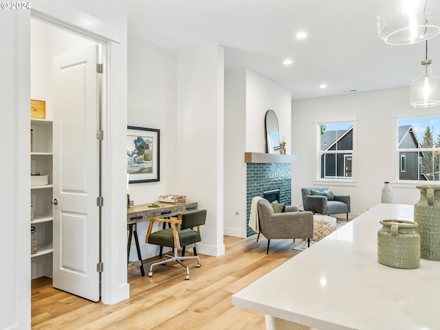 interior space featuring decorative backsplash, decorative light fixtures, a fireplace, and light wood-type flooring