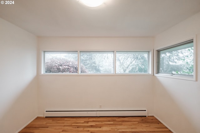 spare room with baseboard heating, plenty of natural light, and light hardwood / wood-style floors