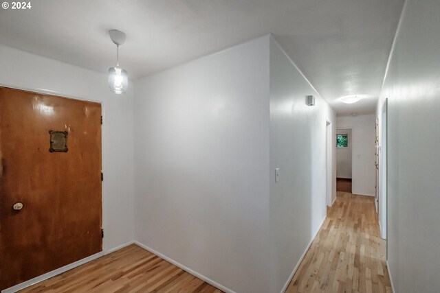 unfurnished living room featuring light hardwood / wood-style flooring, a baseboard radiator, and a brick fireplace