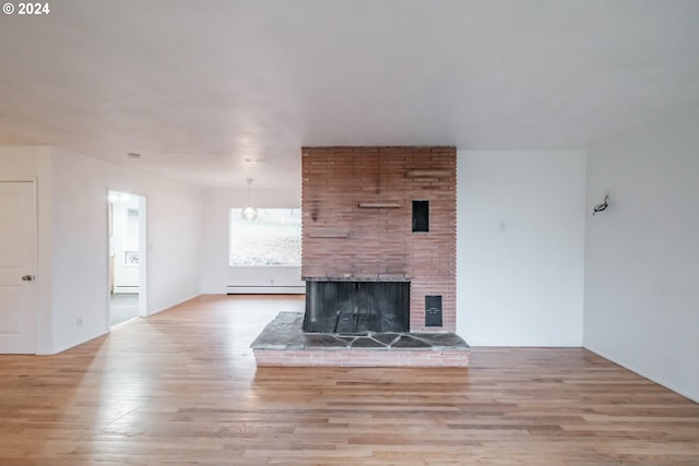 unfurnished living room featuring a brick fireplace, light hardwood / wood-style floors, and a baseboard heating unit