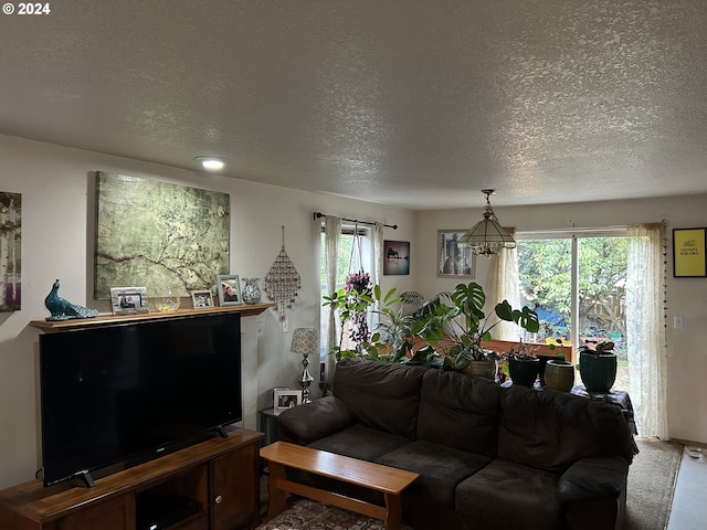 living room featuring plenty of natural light, carpet floors, a textured ceiling, and a notable chandelier