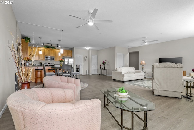 living room with a textured ceiling, ceiling fan, and light hardwood / wood-style flooring