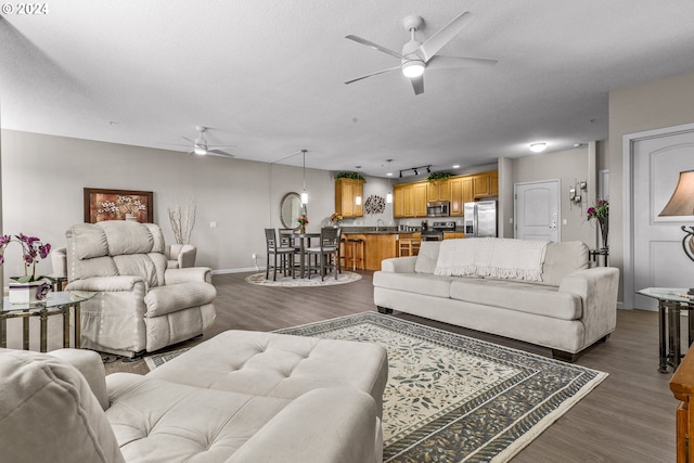 living room with dark hardwood / wood-style flooring, a textured ceiling, and ceiling fan