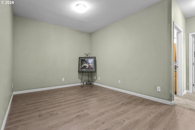 empty room with light hardwood / wood-style floors and a textured ceiling