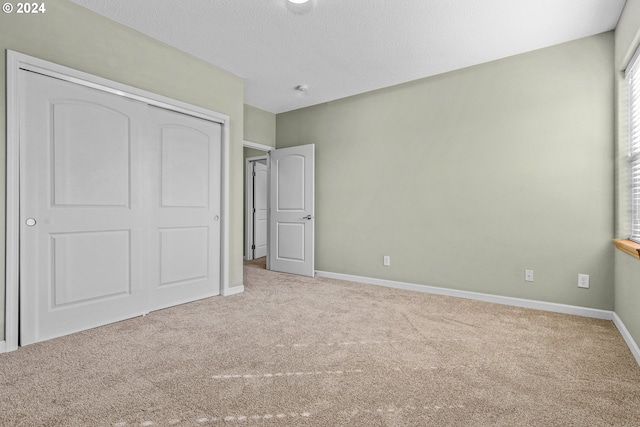 unfurnished bedroom with light carpet, a closet, and a textured ceiling