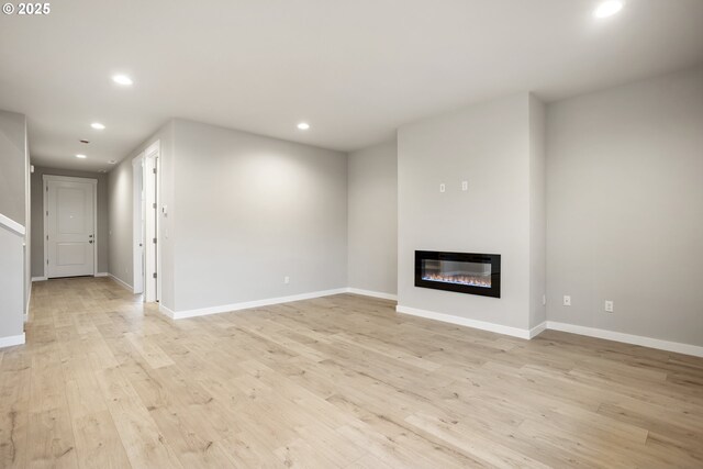 unfurnished living room featuring light wood-type flooring and a tiled fireplace