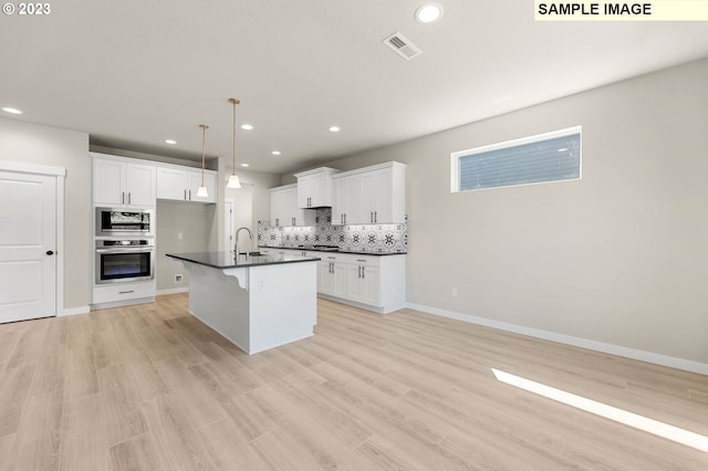 kitchen featuring stainless steel appliances, white cabinetry, a center island with sink, and sink