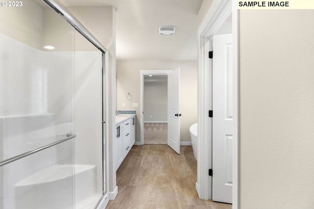 bathroom featuring walk in shower, vanity, and hardwood / wood-style floors