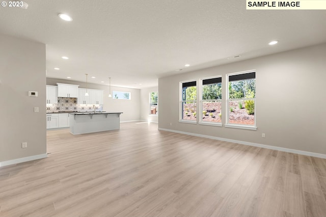 unfurnished living room featuring a textured ceiling and light hardwood / wood-style flooring