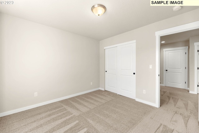 unfurnished bedroom featuring light carpet and a closet