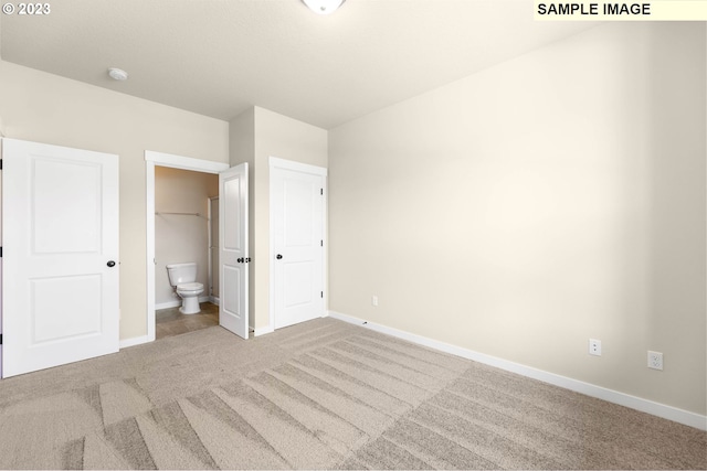 unfurnished bedroom with ensuite bath, a closet, and light colored carpet