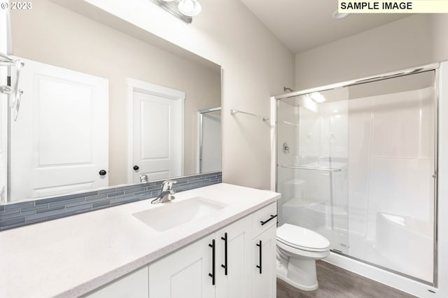 bathroom featuring walk in shower, wood-type flooring, vanity, and toilet