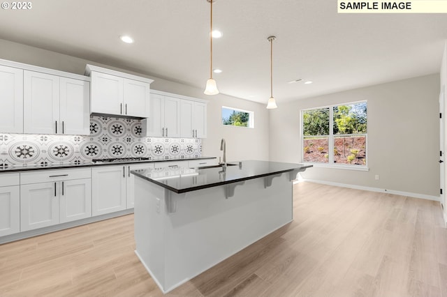 kitchen with decorative backsplash, white cabinets, light hardwood / wood-style flooring, and decorative light fixtures