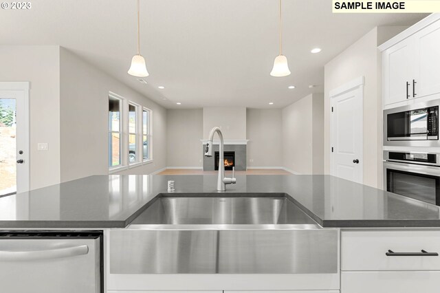 kitchen featuring white cabinetry, sink, pendant lighting, and stainless steel appliances