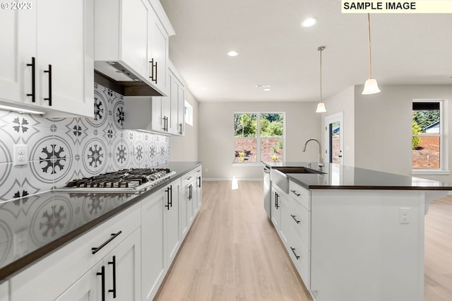 kitchen with a center island with sink, white cabinetry, sink, and plenty of natural light