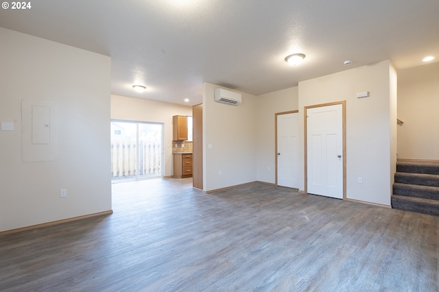 unfurnished room featuring electric panel, wood-type flooring, and a wall mounted air conditioner