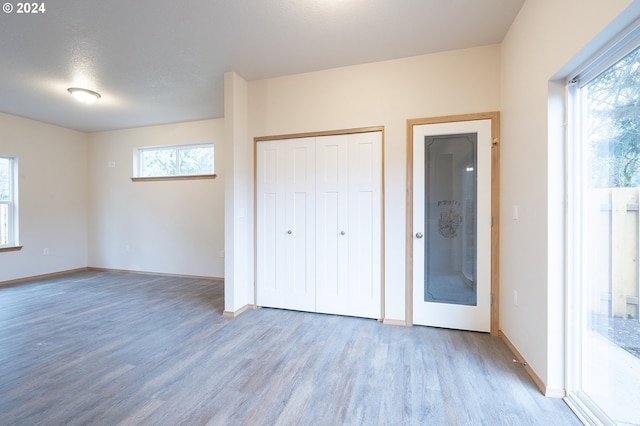 unfurnished bedroom with light wood-type flooring, a textured ceiling, and a closet