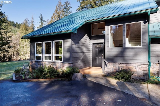 view of front of house featuring stone siding, a standing seam roof, and metal roof