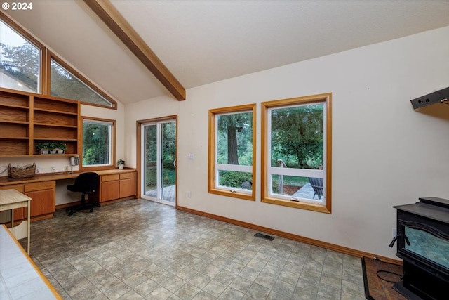 office area featuring vaulted ceiling with beams, tile patterned flooring, built in desk, and a wood stove