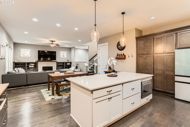 kitchen featuring dark hardwood / wood-style flooring, white refrigerator, stainless steel microwave, and hanging light fixtures