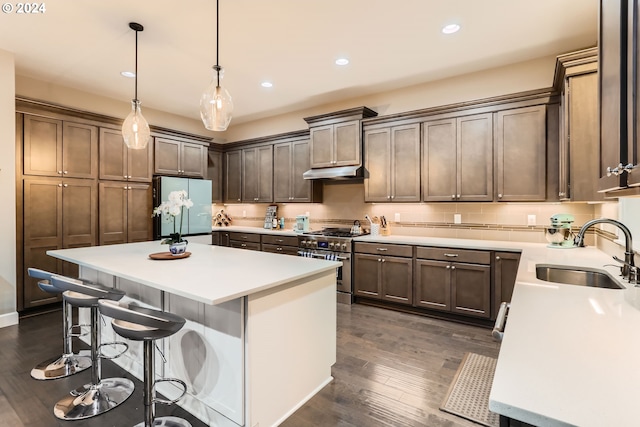 kitchen with white refrigerator with ice dispenser, sink, stainless steel stove, a kitchen island, and dark hardwood / wood-style flooring