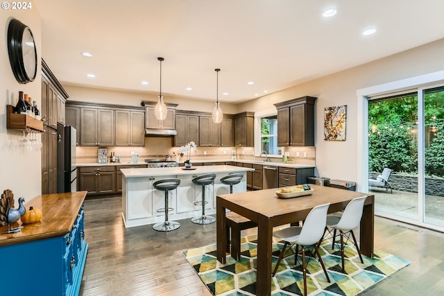 kitchen featuring pendant lighting, a kitchen island, plenty of natural light, and dark wood-type flooring