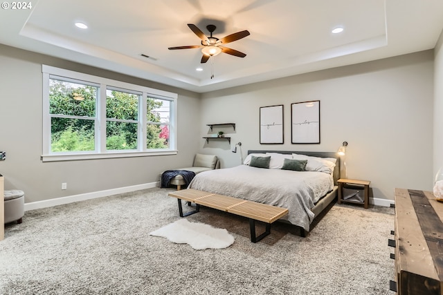 bedroom featuring carpet, a tray ceiling, and ceiling fan