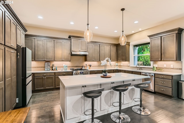 kitchen with a center island, sink, stainless steel appliances, dark hardwood / wood-style floors, and pendant lighting